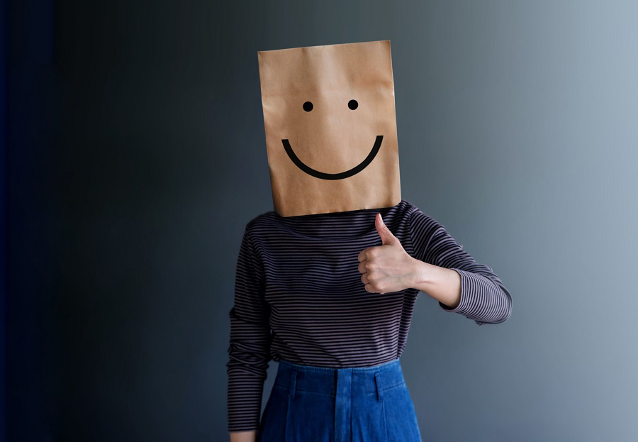 Shy person wearing a paper bag with a smiley face, representing overcoming public speaking anxiety and gaining confidence