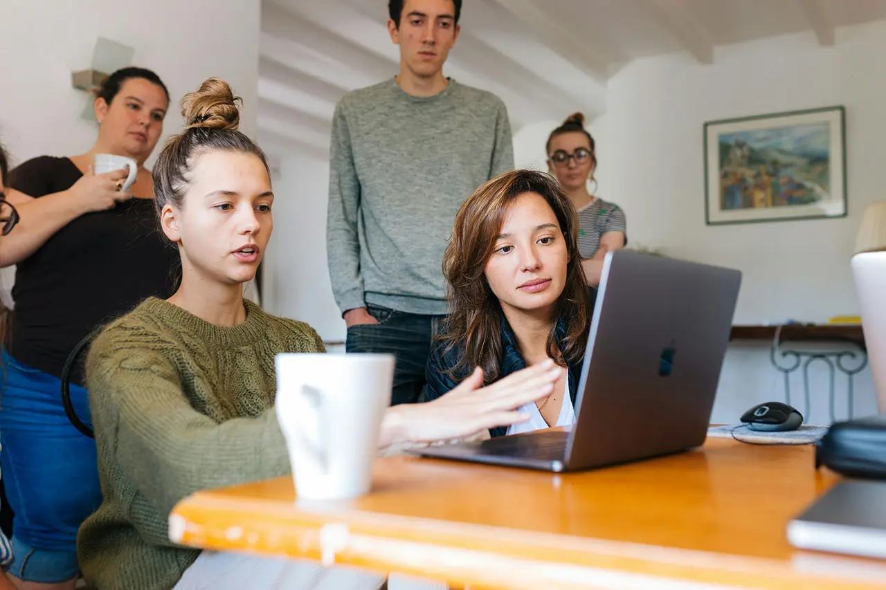 Team of designers and tech enthusiasts collaborating on a laptop, representing hiCreo.ai's vision to revolutionize presentation design with AI.