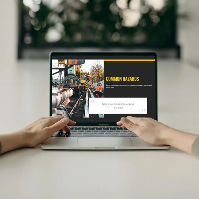 Hands on a laptop displaying a hiCreo presentation slide about common hazards in construction, illustrating the use of visually stunning and clear communication slides.